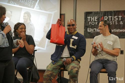 Panelist Shyan Selah accepts his goodie bag of snacks next to Candice Richardson, A'Noelle Jackson and John Silva at The Artist Workshop: Career Day.