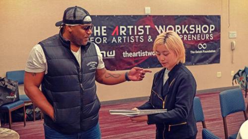 Founder Shyan Selah discusses art with an attendee at The Artist Workshop: The Long Money Game.