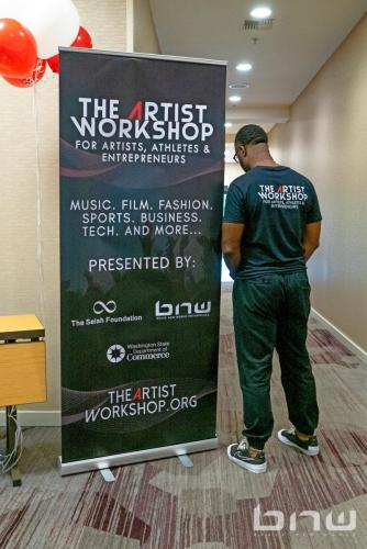 Staffer Darion Dotson finishes setting up the banner at The Artist Workshop: The Musician.